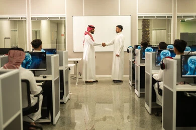 تبادل الخبرات والافكار، معلم عربي خليجي سعودي يرتدي الثوب التقليدي والشماغ يقوم بمناقشة الدروس مع طلابه, مجموعة من الموظفين العربيين الخليجيين السعوديين يرتدون الثوب التقليدى يعملون أمام أجهزة الحاسوب في مقر الشركة