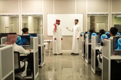 المشاركة والتعاون وتبادل الآراء بين زملاء العمل,  معلم عربي خليجي سعودي يرتدي الثوب التقليدي والشماغ يقوم بمناقشة الدروس مع طلابه, مجموعة من الموظفين العربيين الخليجيين السعوديين يرتدون الثوب التقليدى يعملون أمام أجهزة الحاسوب في مقر الشركة