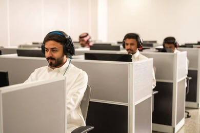 حل مشكلات العملاء عبر التواصل المباشر، مجموعة من الموظفين العربيين الخليجيين السعوديين يرتدون الثوب التقليدى يعملون أمام أجهزة الحاسوب في مقر الشركة, طلاب عرب يجلسون أمام أجهزة الكومبيوتر في مختبر حديث, استخدام تقنية الهيدفون