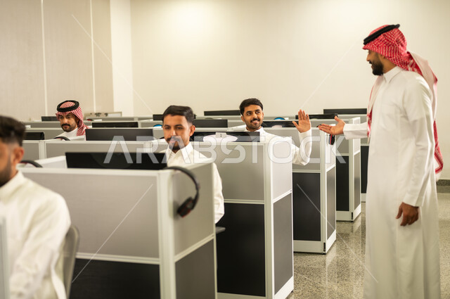 التعليم عبر الحاسوب الجامعي، مجموعة من الطلاب العرب الخليجيون السعوديون يرتدون الثوب التقليدى يجلسون أمام أجهزة الحاسوب في مختبر حديث,  مشاركة الطالب بواسطة رفع الايدي, التعليم في المملكة العربية السعودية