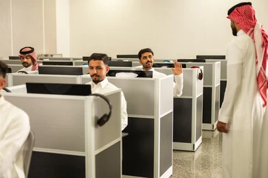 الدراسة الرقمية في المدارس، مجموعة من  الطلاب العرب الخليجيون السعوديون يجلسون امام الحاسوب يقومون بالإستماع الى المحاضره، أستاذ جامعي عربي خليجي سعودى يرتدي الثوب و الشماغ يشرح لطلابه في الفصل الدراسى