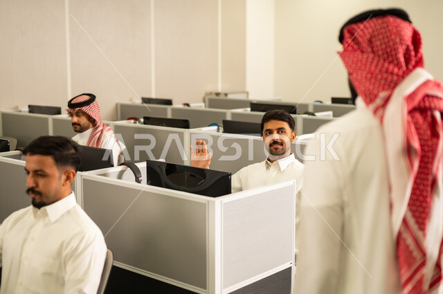 الحصص الدراسية عبر الكمبيوتر،مجموعة من  الطلاب العرب الخليجيين السعوديين يرتدون الثوب التقليدى يجلسون أمام أجهزة الكمبيوتر في مختبر حديث، التركيز على الدراسة والتفاعل الأكاديمي