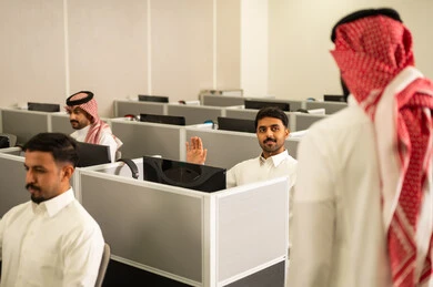 الحصص الدراسية عبر الكمبيوتر،مجموعة من  الطلاب العرب الخليجيين السعوديين يرتدون الثوب التقليدى يجلسون أمام أجهزة الكمبيوتر في مختبر حديث، التركيز على الدراسة والتفاعل الأكاديمي