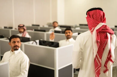 استخدام الحاسوب للتعلم المدرسى،مجموعة من  الطلاب العرب الخليجيون السعوديون يرتدون الثوب التقليدى يجلسون أمام أجهزة الكمبيوتر في مختبر حديث، التركيز على الدراسة والتفاعل الأكاديمي