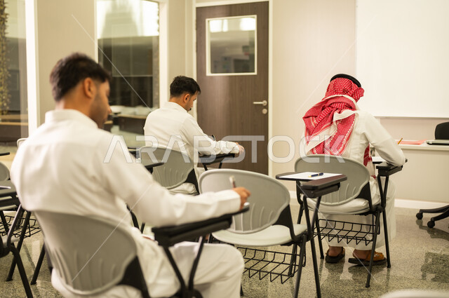 Expressions of engagement and focus; a Saudi Arabian student from the Gulf region answers exam questions; maintaining quiet in the classroom; education in the Kingdom of Saudi Arabia