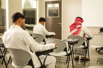 Expressions of engagement and focus; a Saudi Arabian student from the Gulf region answers exam questions; maintaining quiet in the classroom; education in the Kingdom of Saudi Arabia