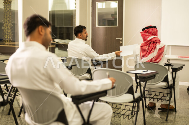 تسليم أوراق الامتحان, معلم عربي خليجي سعودي يقوم بمساعدة الطلاب, متابعة الطلاب أثناء أداء الاختبارات، أهداف التربية والتعليم، التعليم بالمملكة العربية السعودية