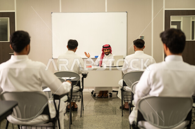 تطور طرق التدريس في مدارس السعودية, طلاب عربيين خليجيين سعوديين يجلسون في مقاعدهم وأمامهم مدرس سعودى يستخدم الحاسوب