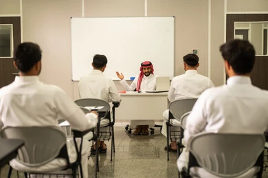 تطور طرق التدريس في مدارس السعودية, طلاب عربيين خليجيين سعوديين يجلسون في مقاعدهم وأمامهم مدرس سعودى يستخدم الحاسوب