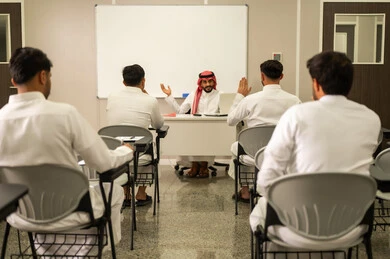 تعابير وايماءات الحماس لمعرفة الجواب الصحيح, طلاب عرب خليجيون سعوديون يقومون بحل أسئلة الاختبارات, معلم عربي خليجي سعودي يرتدي الثوب التقليدي والشماغ يقوم بمناقشة الدروس مع طلابه