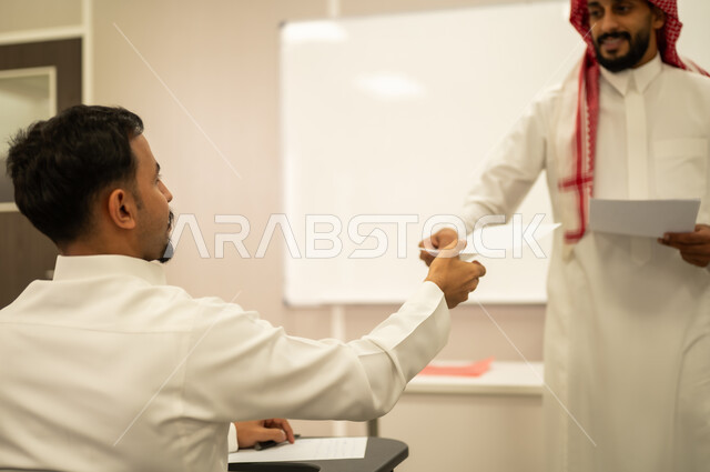 Achievement and success in the educational stage, final exams, students' diligence to achieve excellence, an Arab Gulf Saudi teacher distributing exam papers, a student answering questions, monitoring students during exams, educational goals, end of the academic year, education in the Kingdom of Saudi Arabia