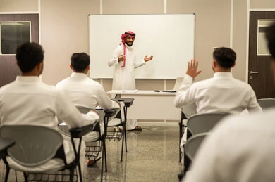 المشاركة الفعالة للطلاب, معلم عربي خليجي سعودي يقوم بشرح الدرس، مجموعة من الطلاب يتفاعلون في الحصة الدراسية من خلال رفع ايديهم للاجابة على اسئلة المدرس، المشاركة الفعالة للطلاب، أهداف التربية والتعليم، التفاعل والمشاركة داخل الفصل الدراسي، التعليم في السعودية
