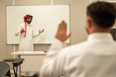 متابعة مجموعة من الطلاب داخل الفصل, معلم عربي خليجي سعودي يقوم بشرح الدرس, التفاعل والمشاركة داخل الفصل الدراسي, طالب عربى سعودى يتفاعل في الحصة الدراسية من خلال رفع يديه للاجابة على اسئلة المدرس، أهداف التربية والتعليم، التعليم في السعودية