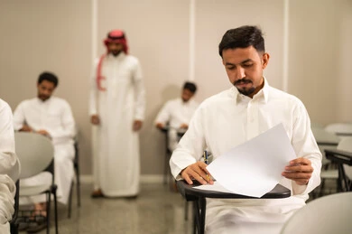 اختبار الطلاب و متابعة اعمالهم خلال الفصل الدراسي , التربية والتعليم , المقررات والمناهج التعليمية الحديثة والمطورة في المملكة العربية السعودية, اختبارات نهاية الفصل الدراسي, طالب عربى خليجى سعودى يرتدى الثوب التقليدى يقوم بحل اسئلة الاختبار, التعليم في المملكة العربية السعودية, اهداف التربية و التعليم