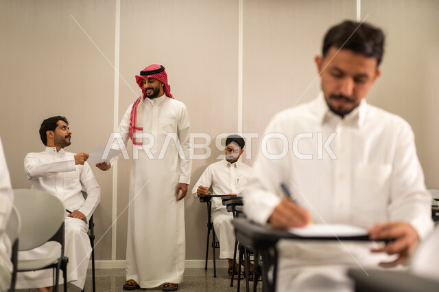 Gestures of integration and focus, modern and developed educational curricula and programs in the Kingdom of Saudi Arabia, end-of-term exams, a Saudi Arabian Gulf student wearing traditional attire taking exam questions, education in the Kingdom of Saudi Arabia, goals of education