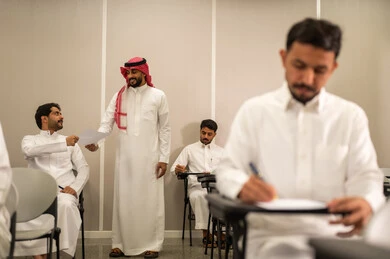 ايماءات الاندماج و التركيز , المقررات والمناهج التعليمية الحديثة والمطورة في المملكة العربية السعودية, اختبارات نهاية الفصل الدراسي, طالب عربى خليجى سعودى يرتدى الثوب التقليدى يقوم بحل اسئلة الاختبار, التعليم في المملكة العربية السعودية, اهداف التربية و التعليم