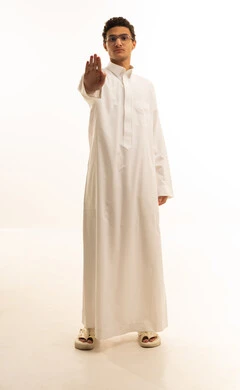 A portrait of a Saudi Arabian Gulf man wearing traditional attire, raising his hand upwards in a stop gesture, showing signs of fear, anxiety, and discomfort about something, expressing disapproval and rejection of harm, requesting to stop and refrain from doing something, with a white background.