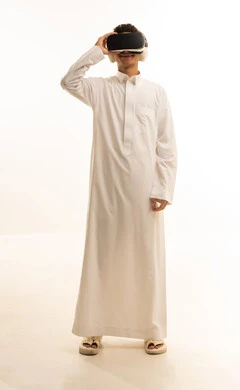 Wearing virtual reality glasses, simulating the imaginary world, using modern technological devices, a portrait of an Arab Gulf Saudi man wearing traditional attire and wearing 3D VR glasses, having a good time playing video games, white background.