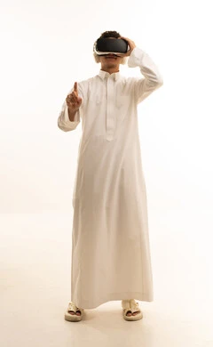 A portrait of a Saudi Arabian Gulf man wearing traditional attire, wearing 3D VR glasses, having a good time playing video games, simulating a fantasy world, wearing virtual reality glasses, using modern technological devices, with a white background.