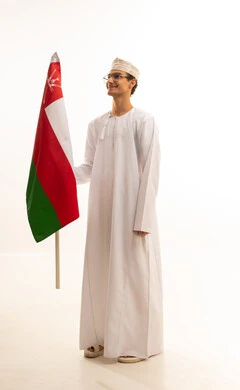 الاحتفال بذكرى اليوم الوطني العماني، ثقافات ورموز وطنية, مفهوم حب الوطن والإنتماء إليه، الاعتزاز والفخر بالرموز والراية العمانية، بورتريه لشاب عربي خليجي عماني يرتدي الدشداشة والكمة ونظارات طبية  يمسك بيده علم سلطنة عمان ، الجسم بالطول الكامل، خلفية بيضاء .