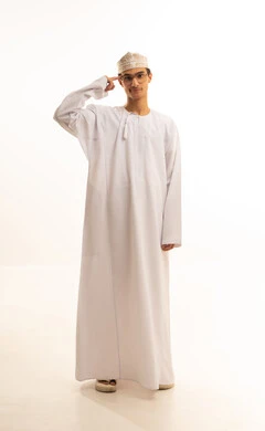 الإصرار على الرأي و فعل ما يرغب, مفهوم التفكير والتحليل و الذكاء والفطنة, بورتريه لشاب عربي خليجي عماني يرتدي الدشداشة والكمة ونظارات طبية يشير بإصبع السبابة إلى رأسه بتعابير العناد, خلفية بيضاء