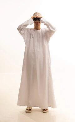 رؤية الاشياء البعيدة عبر التلسكوب بايماءات الاندهاش والسرور، التخطيط المستقبلي للأهداف والطموحات، بورتريه لرجل عربي خليجي عماني يرتدي الدشداشة والكمة  ينظر من خلال منظار الرؤية ثنائي العينين, حب الاستكشاف والمغامرة، خلفية بيضاء