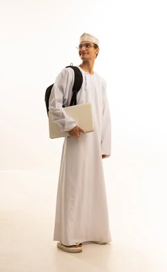 بورتريه لرجل عربي خليجي عماني يرتدي الدشداشة والكمة ونظارات طبية يضع حقيبة الظهر يمسك بيده جهاز اللابتوب، مفهوم التعليم عن بعد، المواد والمناهج التعليمية في المملكة، متابعة المحاضرات عبر المنصات التعليميه المتطوره،صورة لكامل الجسم، خلفية بيضاء