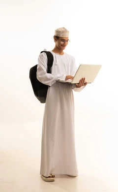 متابعة المحاضرات عبر المنصات التعليميه المتطوره، مفهوم التعليم عن بعد، المواد والمناهج التعليمية في المملكة،بورتريه لرجل عربي خليجي عماني يرتدي الدشداشة والكمة ونظارات طبية يضع حقيبة الظهر يمسك بيده جهاز اللابتوب، صورة لكامل الجسم، خلفية بيضاء