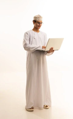 استخدام جهاز تقني حديث , دمج التكنولوجيا المتطورة فى الحياة اليومية ،وظيفة ومهنة عمانية شبابية, بورتريه لرجل عربي خليجي عماني يرتدي الكمه و الدشداشة ونظارات طبية يستخدم جهاز الحاسوب المحمول, خلفية بيضاء