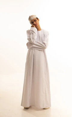 الشعور بالخيبة والانزعاج، إيماءات الحزن والإحباط، الندم على شيء ما، بورتريه لشاب عربي عماني يرتدي الدشداشة والكمة ونظارات طبية  ينظر الى الكاميرا بتعابير العبوس, خلفية بيضاء