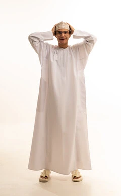 إيماءات الحزن والإحباط، الشعور بالخيبة والانزعاج،  الندم على شيء ما، بورتريه لشاب عربي عماني يرتدي الدشداشة والكمة ونظارات طبية يضع يده على رأسه بتعابير العبوس, خلفية بيضاء