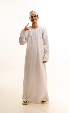 تجميل وتبييض الأسنان، بورتريه لشاب عربي خليجي عماني يرتدي الدشداشة والكمة ونظارات طبية  يشير بإصبع السبابة على أسنانه البيضاء، مفهوم العناية والإهتمام بالصحة والمظهر الخارجي ، الحصول على إبتسامة هوليود باستخدام قشور فينير من الخزف، خلفية بيضاء