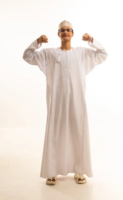 إستعراض القوة البدنية ، لياقة بدنية وصحة، بورتريه لرجل عربي خليجي عماني يرتدي الدشداشة والكمة ونظارات طبية  يرفع يده بكفه مقبوضه ، مفهوم القوة العضلية وعرض العضلات ، خلفية بيضاء