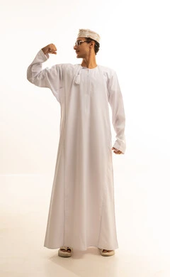 لياقة بدنية وصحة، إستعراض القوة البدنية ،بورتريه لرجل عربي خليجي عماني يرتدي الدشداشة والكمة ونظارات طبية  يرفع يده بكفه مقبوضه ، مفهوم القوة العضلية وعرض العضلات ، خلفية بيضاء