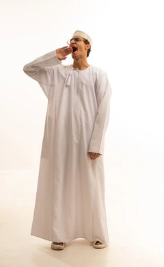 تعابير النعاس والحاجه الى النوم، بورتريه لشاب عربي خليجي عماني يرتدي الدشداشة والكمة يرفع يديه بإيماءات النعاس, الإحساس بالتعب والتثاؤب ,مفهوم الكسل والخمول، خلفيه بيضاء