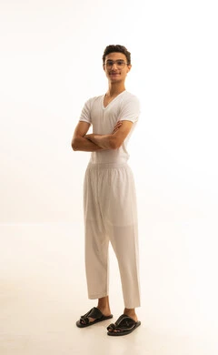 الوقوف بايدي متقاطعة، مفهوم الرجولة والأناقة، الاهتمام بالمظهر الخارجي، بورتريه لرجل عربي خليجي سعودي يرتدي السروال والفانيلة البيضاء  ينظر الى الكاميرا  بايماءات السعادة ، الجسم بالطول الكامل، خلفية بيضاء