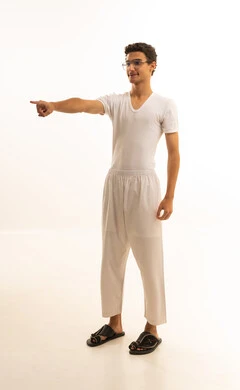 Movements indicating this place (here), indicating a specific location, identifying the place of a specific element, a portrait of a Saudi Arabian Gulf Arab man wearing white pants and a white shirt pointing to something, white background.