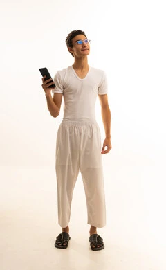 Chatting with friends and relatives via mobile, gestures of joy and happiness, a portrait of a Saudi Arabian Gulf man wearing pants and a white t-shirt holding a mobile phone in his hand, integrating advanced technology into daily life, using a modern and advanced technical device, white background.