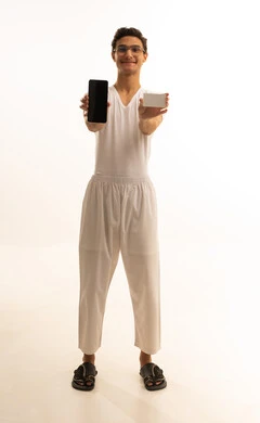 The possibility of paying bills with electronic cards, the ease of purchasing and paying with a bank credit card, a portrait of a Saudi Gulf Arab man wearing pants and a t-shirt holding a white card and working on a mobile phone, white background.