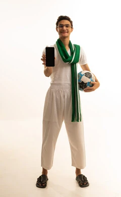 تعابير السرور والسعادة ، استخدام التقنيات الحديثة، مشاهدة ومتابعة مباراة كرة القدم، بورتريه لرجل عربي خليجي سعودي يرتدي السروال والفانيله البيضاء والوشاح يعرض شاشة سوداء فارغة عبر الجوال، أنديه رياضية مختلفة، خلفية بيضاء .