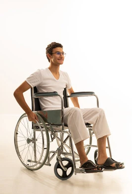 مفهوم الرجولة والأناقة، الاهتمام بالمظهر الخارجي، بورتريه لرجل عربي خليجي سعودي يرتدي السروال والفانيلة البيضاء يجلس على كرسي متحرك ينظر الى شئ ما بايماءات السعادة ، الجسم بالطول الكامل، خلفية سوداء