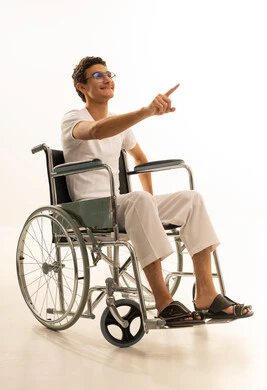 حركات تدل على هذا المكان (هنا), الدلالة على موقع معين, تحديد مكان عنصر محدد, بورتريه لرجل عربي خليجي سعودي يرتدي السروال والفانيله البيضاء يجلس على كرسي متحرك يشير إلى شيء ما,  خلفية بيضاء