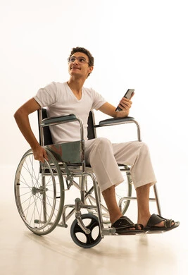 الدردشة مع الأصدقاء والأقارب عبر الجوال، ايماءات الفرح والسعادة، بورتريه لرجل عربي خليجي سعودي يرتدي السروال والفانيله البيضاء يجلس على كرسي متحرك يمسك بيده الهاتف المحمول، قضاء وقت ممتع في المنزل، استخدام جهاز تقني حديث ومتطور، خلفية بيضاء