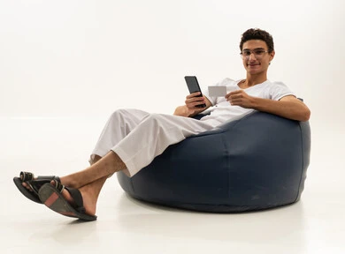 استخدام التقنيات الحديثة، إمكانية تسديد الفواتير بالبطاقات الإلكترونية, سهولة الشراء والدفع عن طريق بطاقة الإئتمان البنكية، بورتريه لرجل عربي خليجي سعودي يرتدي سروال وفنيله يجلس على كرسي مريح ويمسك بيده بطاقة بيضاء ويعمل على الهاتف المحمول، خلفية بيضاء