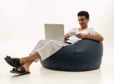 The ease of purchasing and paying via bank credit card, the ability to pay bills with electronic cards, a portrait of an Arab Gulf Saudi man wearing pants and a t-shirt sitting on a comfortable chair holding a white card and working on a laptop, white background.