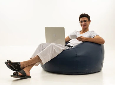 The possibility of paying bills with electronic cards, the ease of purchasing and paying with a bank credit card, a portrait of an Arab Gulf Saudi man wearing pants and a t-shirt sitting on a comfortable chair holding a white card and working on a laptop, white background.