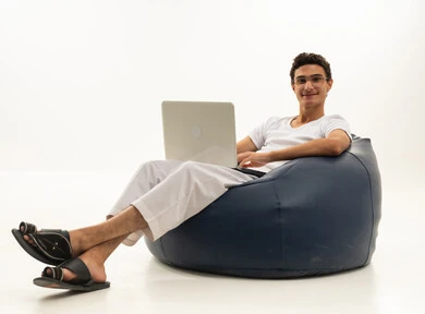 ادارة الأعمال عن بعد، استخدام الأجهزة الحديثة والمتطورة، بورتريه لرجل عربي خليجي سعودي يرتدي السروال والفانيله البيضاء يجلس على كرسي مريح يقوم باستخدام الحاسوب المحمول، دمج التكنولوجيا بالعمل، إنجاز المهام المطلوبة عبر اللابتوب، مهن ووظائف سعودية ، خلفية بيضاء