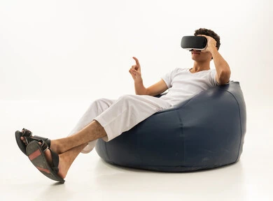 The use of modern technological devices, simulating the imaginary world, wearing virtual reality glasses, a portrait of an Arab Gulf Saudi man wearing white pants and a t-shirt sitting on a comfortable chair wearing 3D VR glasses, having a good time playing video games, white background.