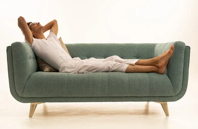 ايماءات التأمل و الاستمتاع بوقت الهدوء, أخذ قسط من الراحة, بورتريه لرجل عربي خليجي سعودي يرتدي السروال والفانيله البيضاء يجلس على اريكة مريحة يضع يديه خلف رأسه بتعابير الاسترخاء , خلفية بيضاء