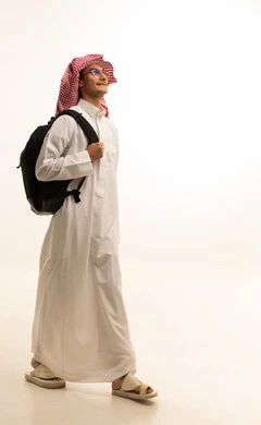 الاستعداد للعام الجامعي الجديد، الجامعات والكليات الأكاديمية،  بورتريه لرجل عربي خليجي سعودي يرتدي الزي التقليدي  والشماغ  وحقيبة الظهر يقوم بمتابعة الدروس اليومية، صورة لكامل الجسم، خلفية بيضاء